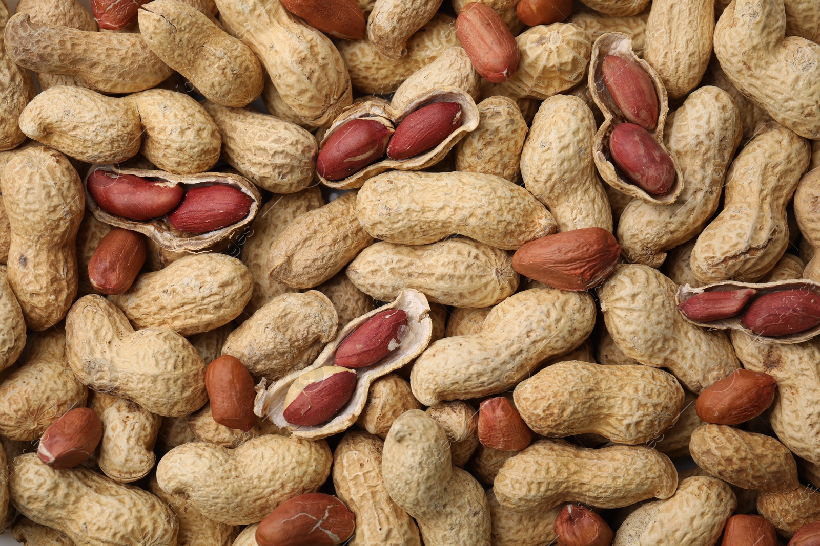 Photo of Many fresh unpeeled peanuts as background, top view