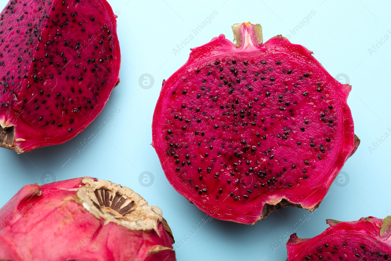 Photo of Delicious cut red pitahaya fruits on light blue background, flat lay