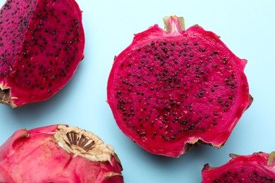 Photo of Delicious cut red pitahaya fruits on light blue background, flat lay