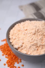 Bowl of lentil flour and seeds on white table, closeup