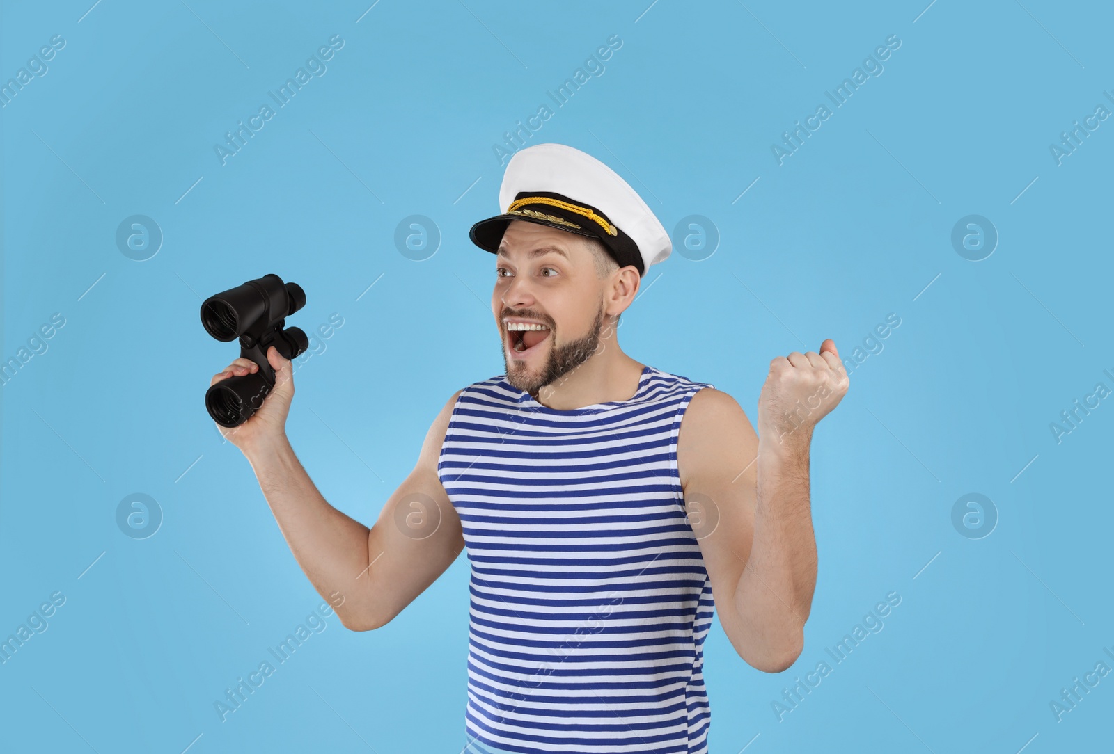 Photo of Happy sailor with binoculars on light blue background