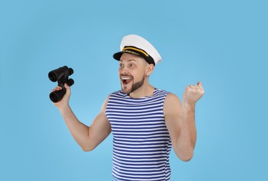 Happy sailor with binoculars on light blue background