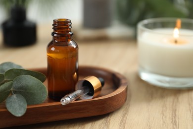 Aromatherapy. Bottle of essential oil and eucalyptus leaves on wooden table, closeup