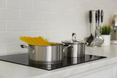 Photo of Saucepan with uncooked pasta on stove in kitchen
