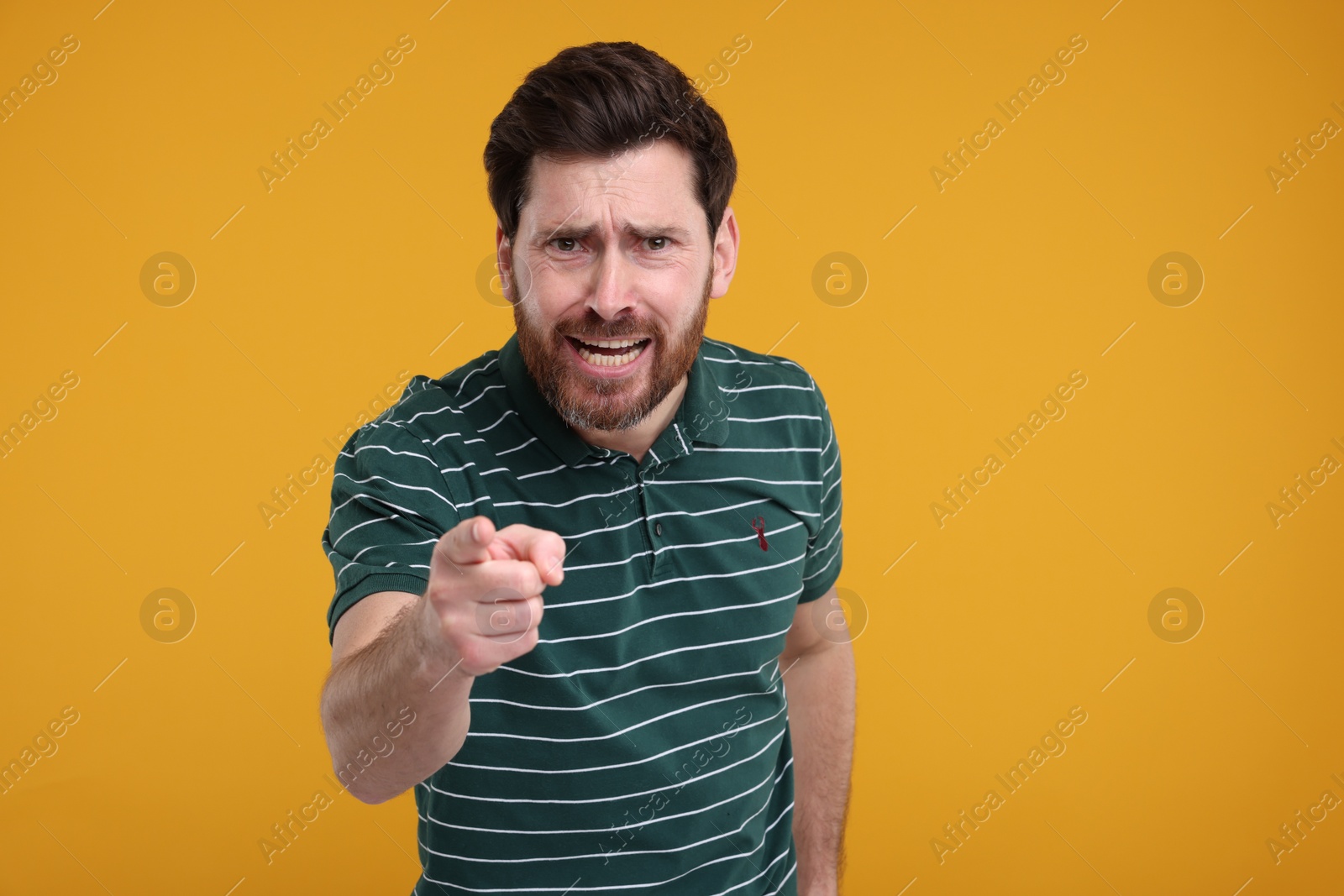 Photo of Surprised man pointing at something on yellow background