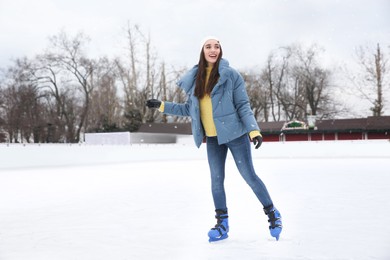 Happy woman skating along ice rink outdoors