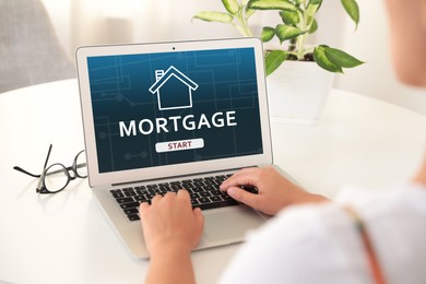 Image of Mortgage concept. Woman using modern laptop at table, closeup