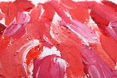 Photo of Beautiful strokes of bright oil paints on white canvas as background, closeup