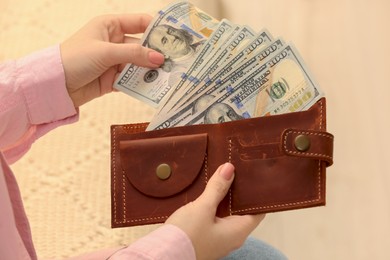 Photo of Woman counting dollar bills on beige background, closeup. Money exchange