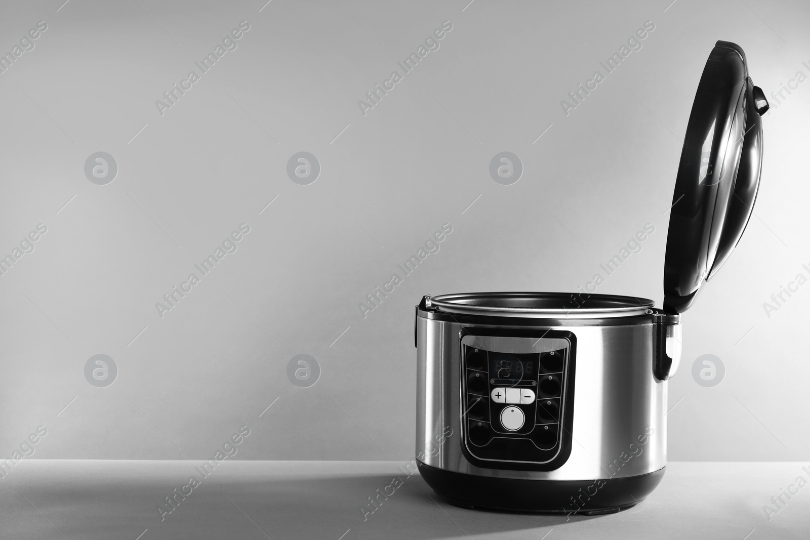 Photo of Modern powerful multi cooker on table against grey background. Space for text