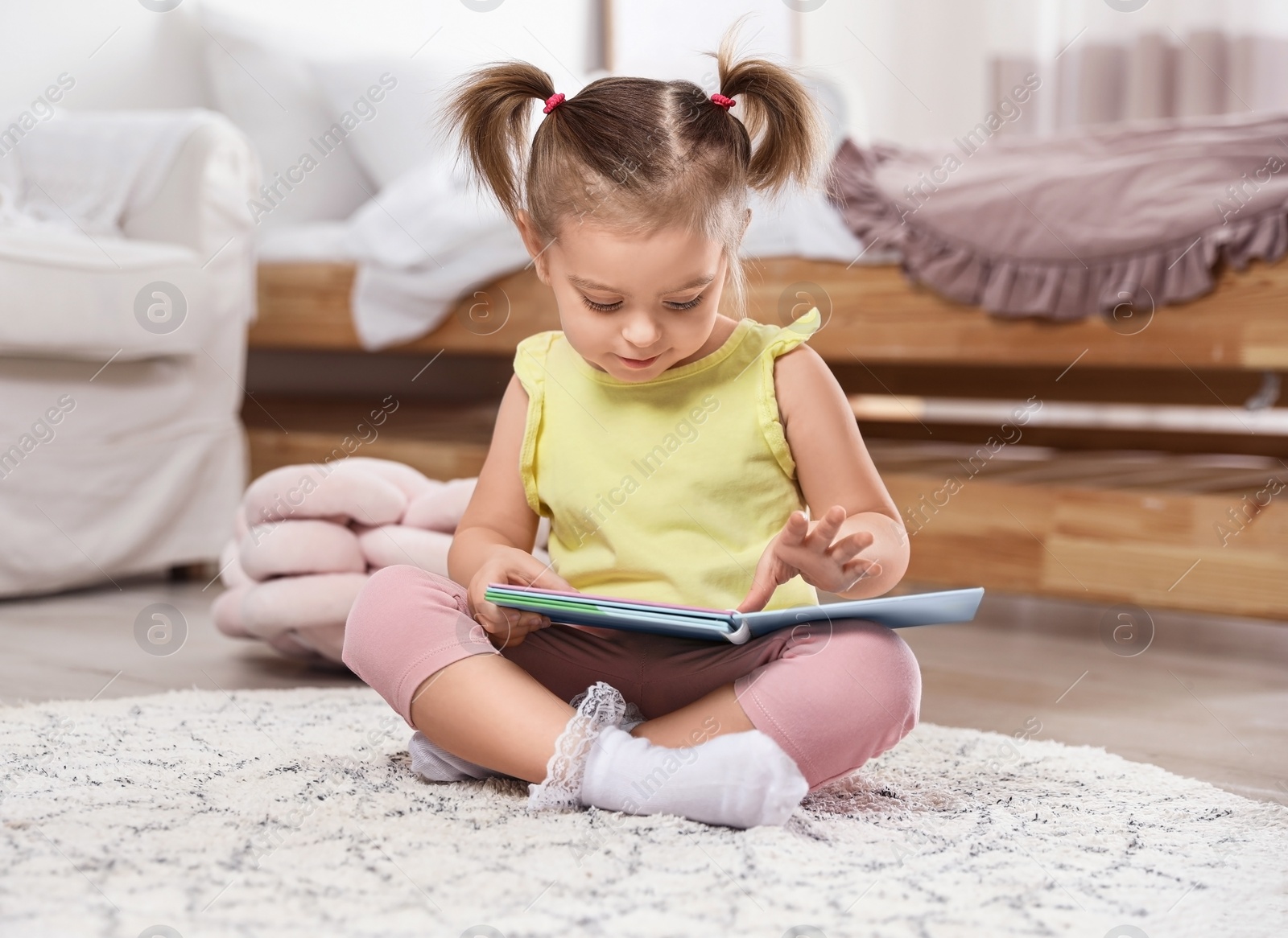 Photo of Cute little girl with book at home