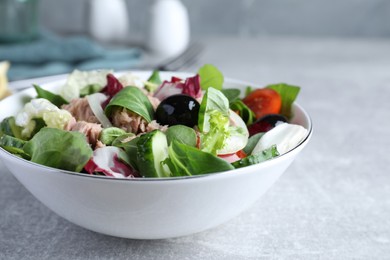 Photo of Bowl of delicious salad with canned tuna and vegetables on light grey table