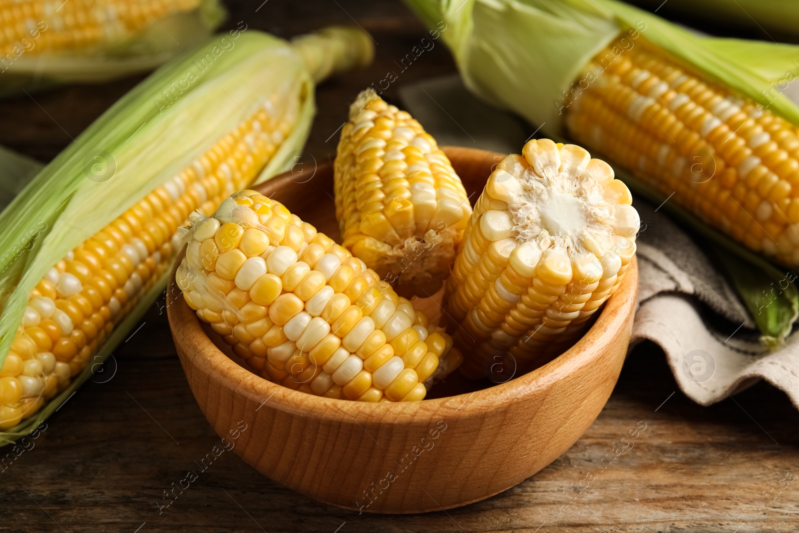 Photo of Tasty sweet corn cobs on wooden table, closeup