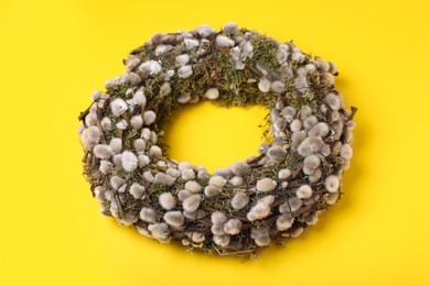 Wreath made of beautiful willow flowers on yellow background