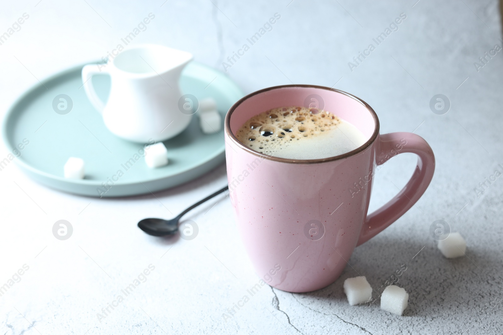 Photo of Tasty coffee in cup and sugar cubes on white textured table, closeup