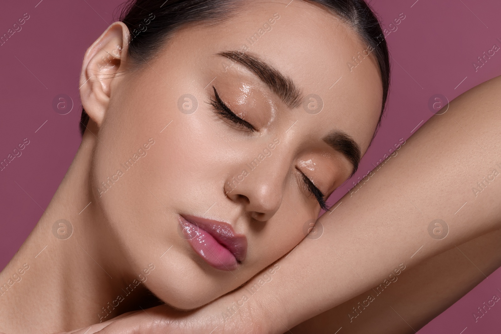 Photo of Portrait of beautiful young woman with perfect makeup on dark pink background, closeup