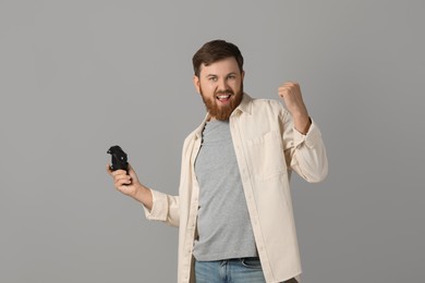 Emotional man with game controller on grey background