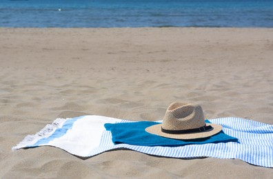 Blue towels and straw hat on sandy beach near sea