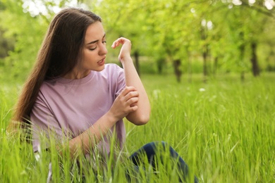 Photo of Young woman scratching hand outdoors, space for text. Seasonal allergy