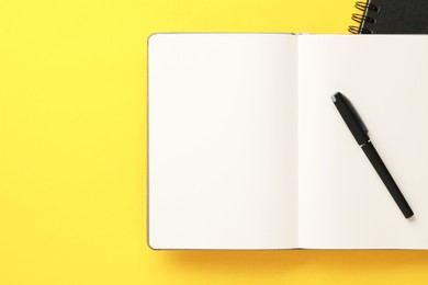 Photo of Notebooks and pen on yellow background, top view. Space for text