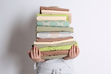 Photo of Woman holding stack of clean bed linens on white background