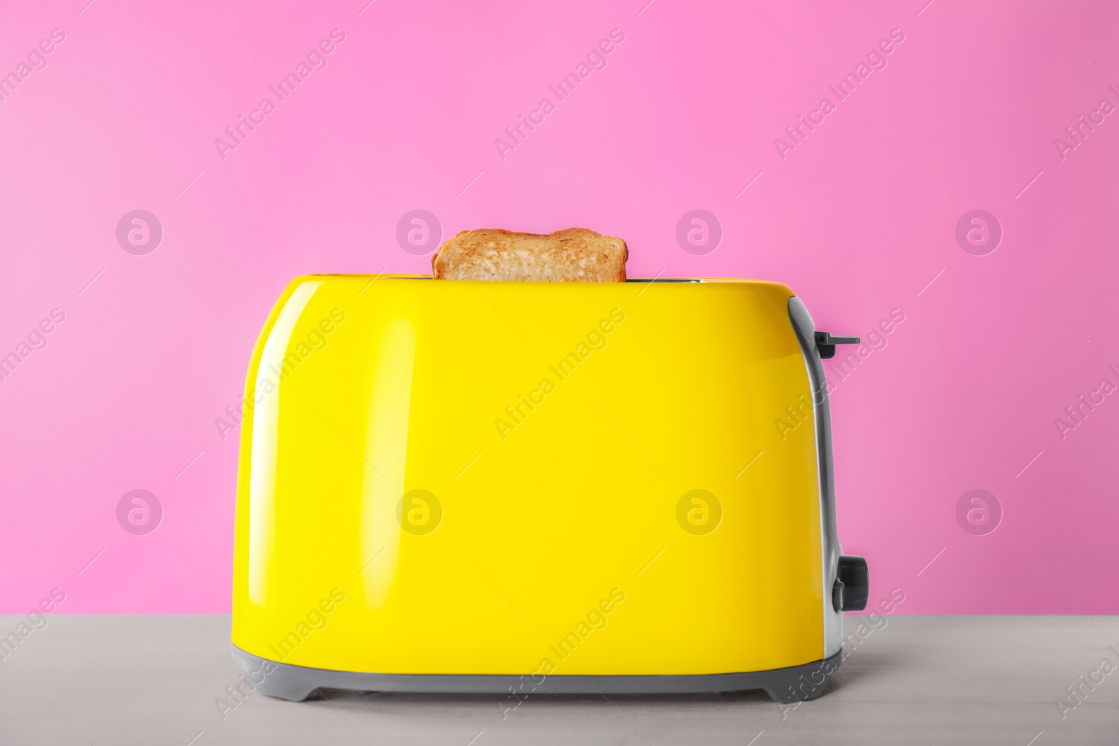 Photo of Modern toaster with slices of roasted bread on white wooden table