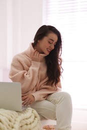 Photo of Beautiful young woman with laptop relaxing at home. Cozy atmosphere