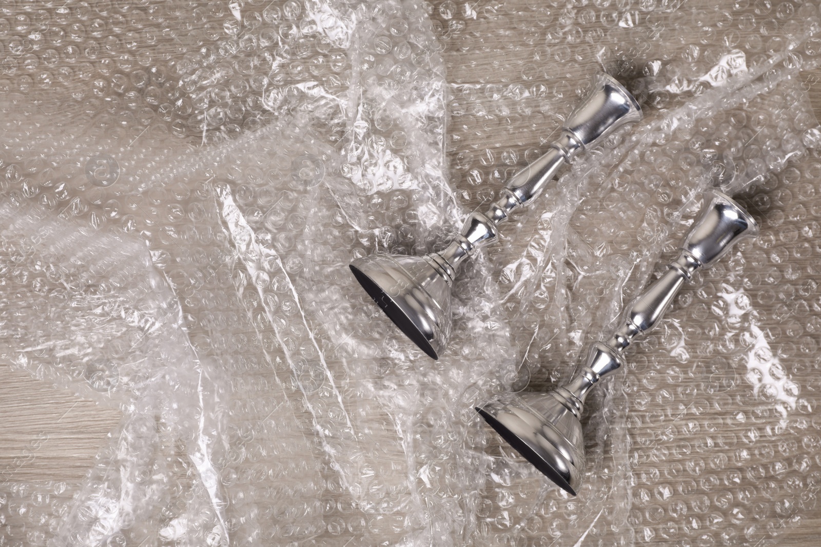 Photo of Candlesticks with bubble wrap on wooden table, flat lay