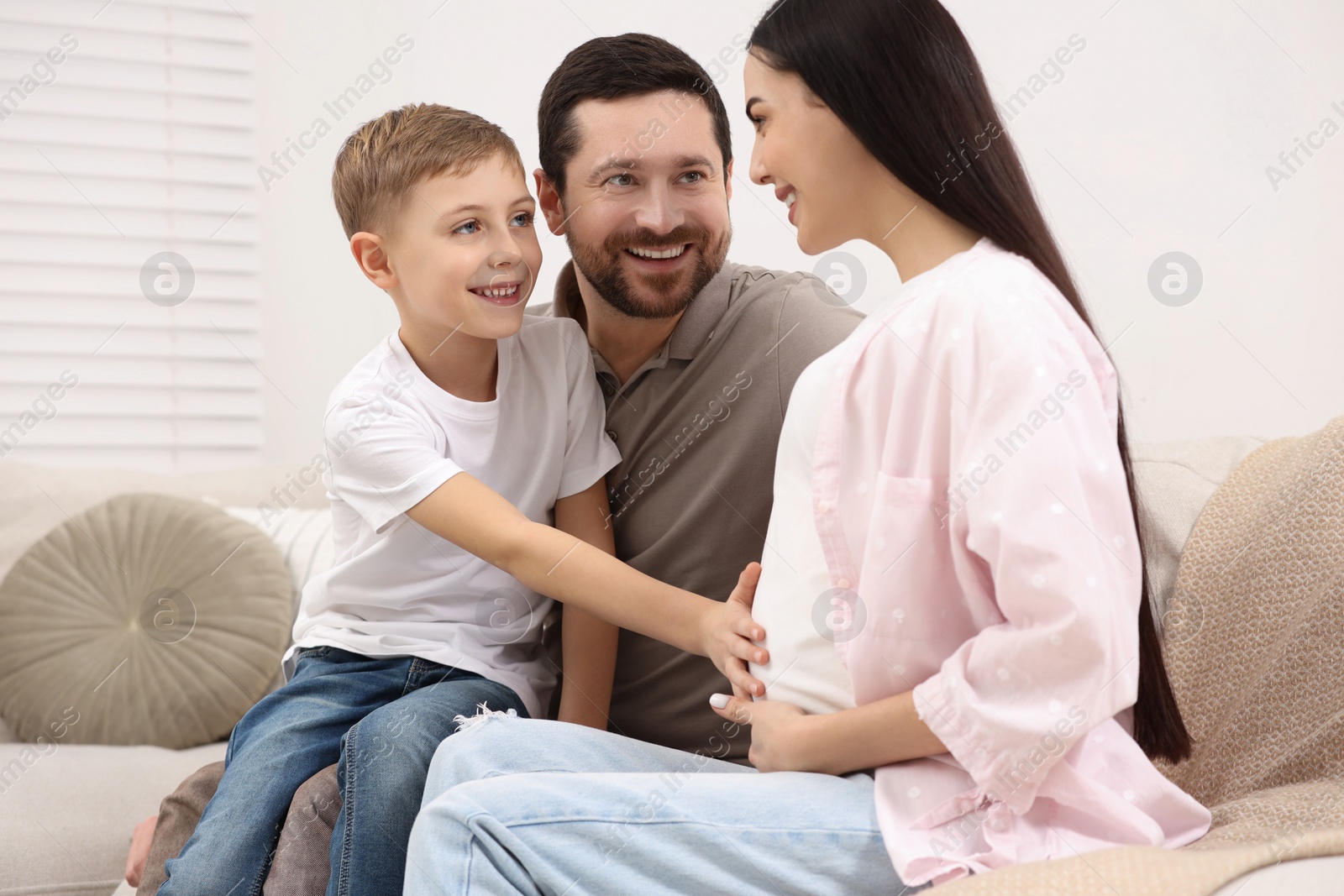 Photo of Happy pregnant woman spending time with her son and husband at home