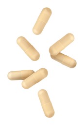 Vitamin. Many capsules falling on white background