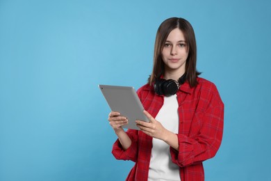 Photo of Beautiful teenage girl with tablet on light blue background. Space for text