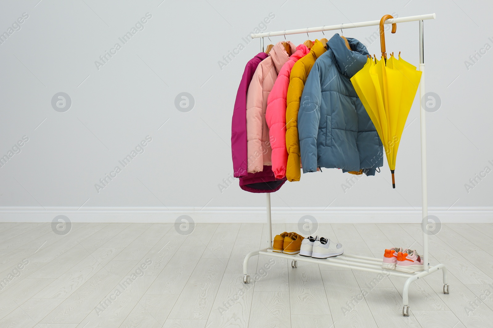 Photo of Rack with warm jackets in room. Space for text