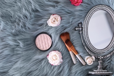 Photo of Flat lay composition with makeup brushes, roses and mirror on faux fur