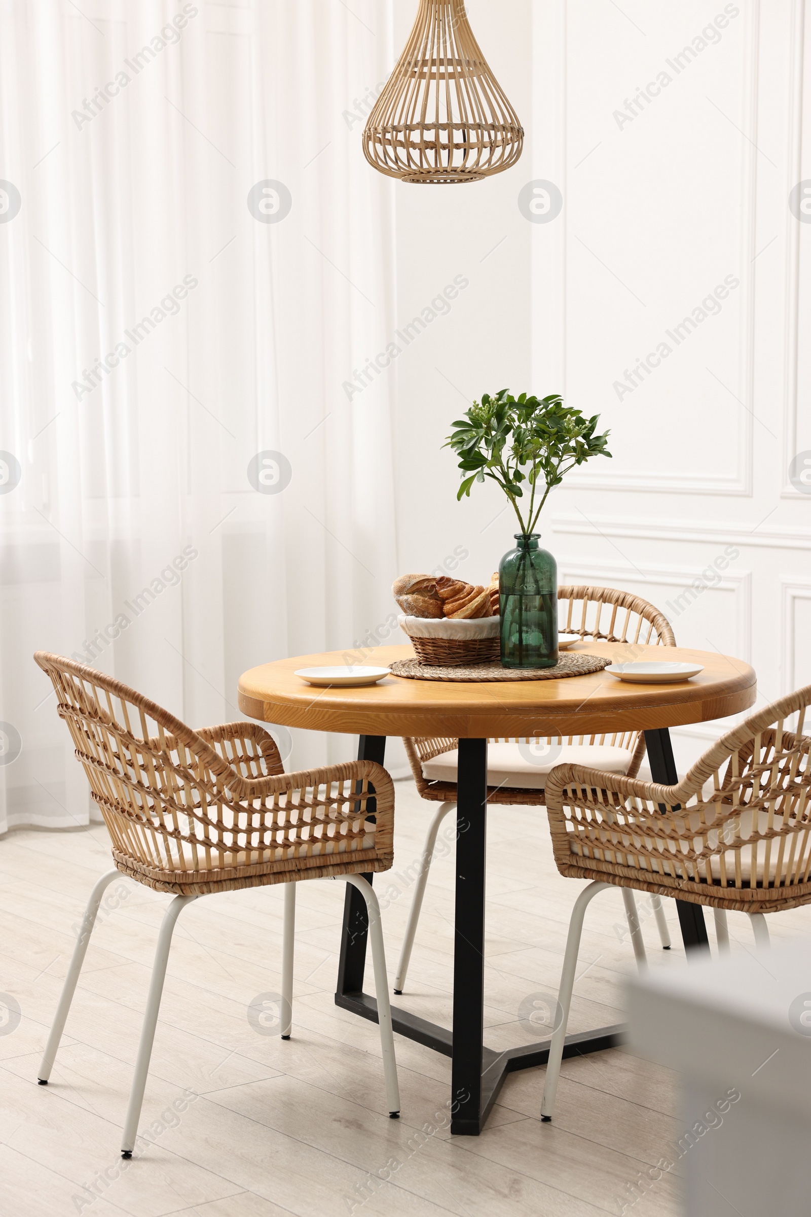 Photo of Dining room interior with comfortable furniture and green branches