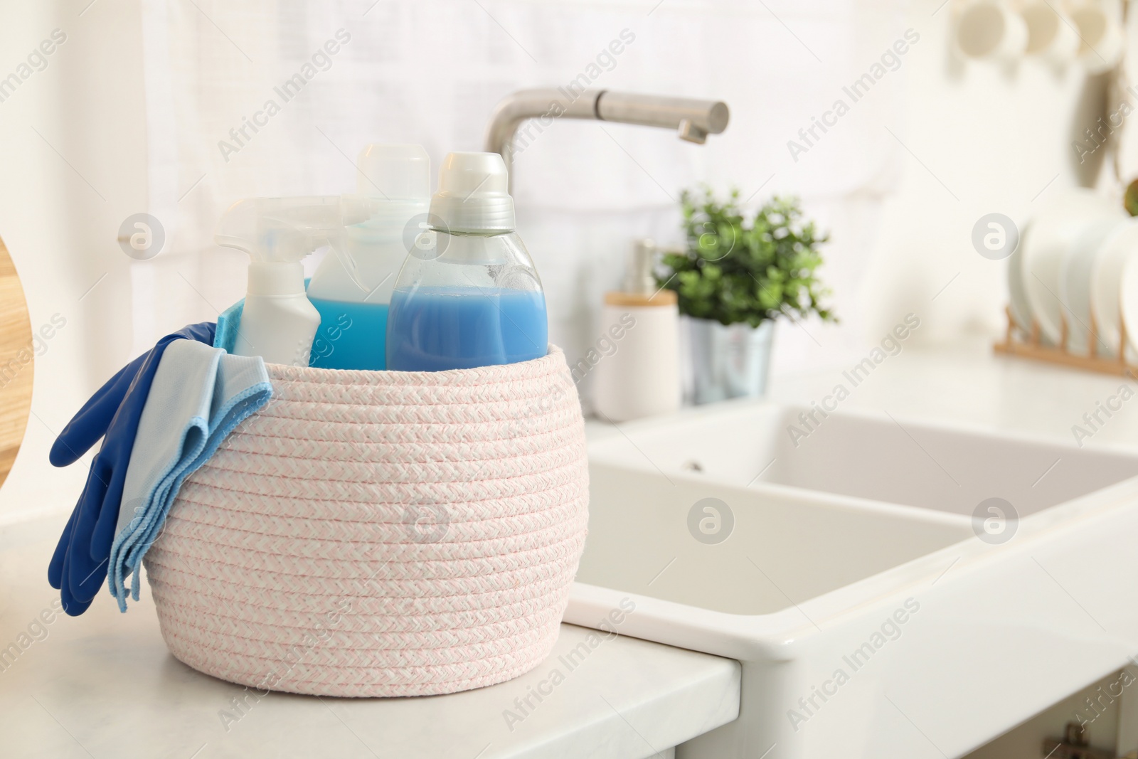 Photo of Different cleaning supplies in basket on countertop