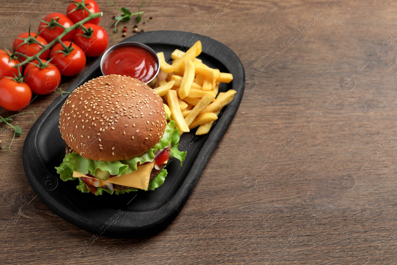 Photo of Delicious burger with beef patty, tomato sauce and french fries on wooden table, above view. Space for text