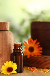 Bottles of essential oils and beautiful calendula flowers on wooden table outdoors, closeup. Space for text