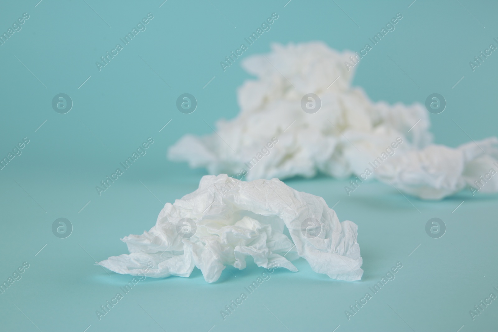 Photo of Used paper tissues on light blue background, closeup