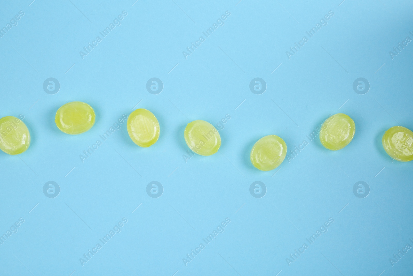 Photo of Many delicious lemon drops on light blue background, flat lay