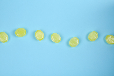 Photo of Many delicious lemon drops on light blue background, flat lay