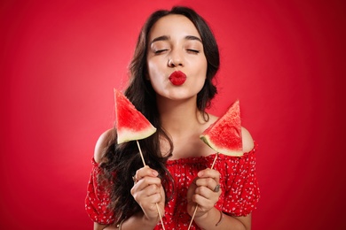 Beautiful young woman with watermelon on red background