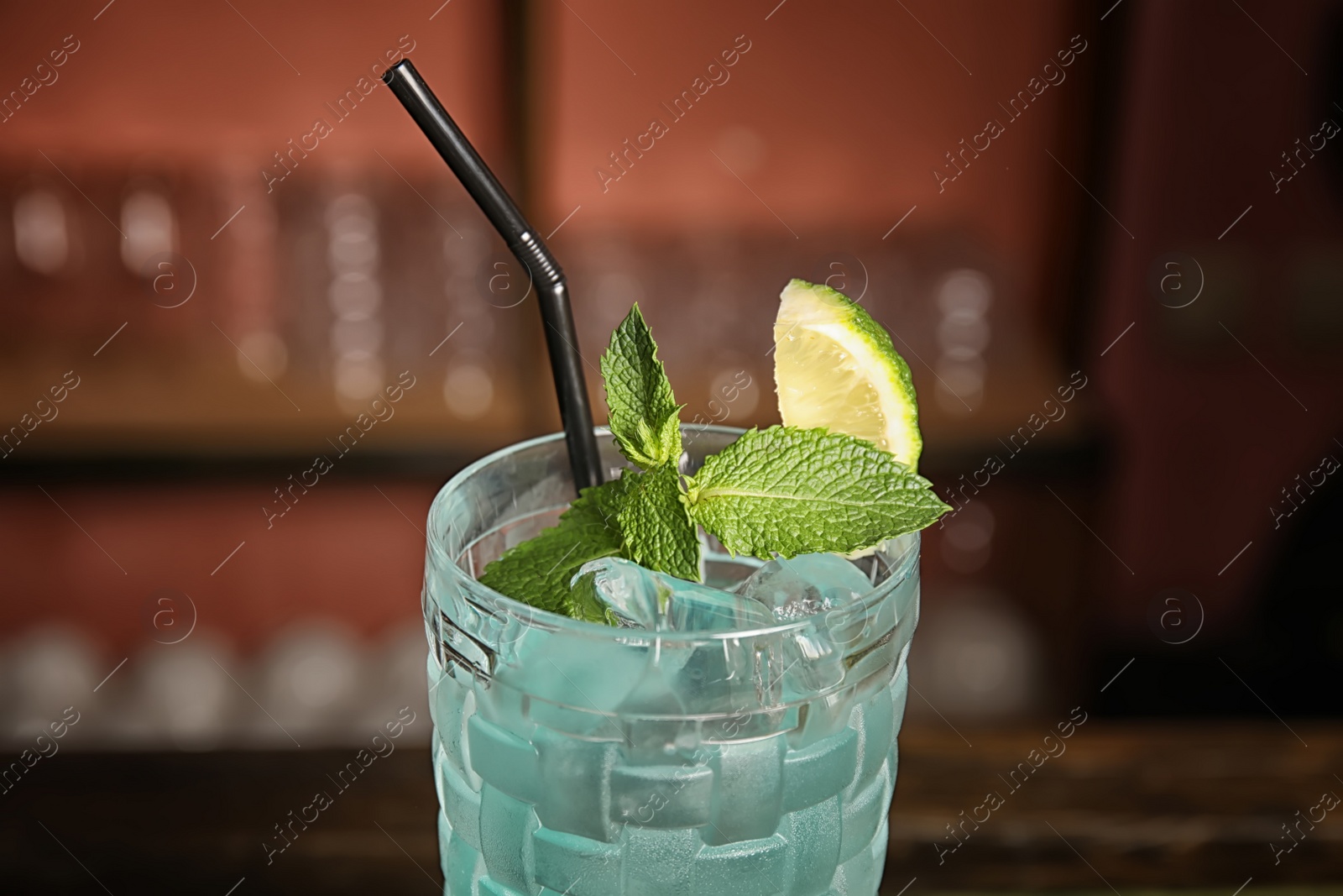 Photo of Glass with delicious cocktail on blurred background