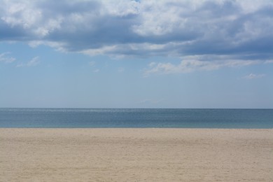 Photo of Picturesque view of sandy beach near calm sea on cloudy day
