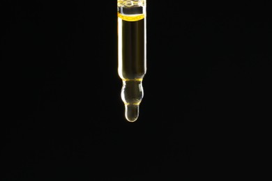 Photo of Pipette with tincture on black background, closeup