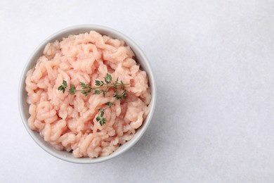 Photo of Fresh raw minced meat and thyme in bowl on light grey table, top view. Space for text