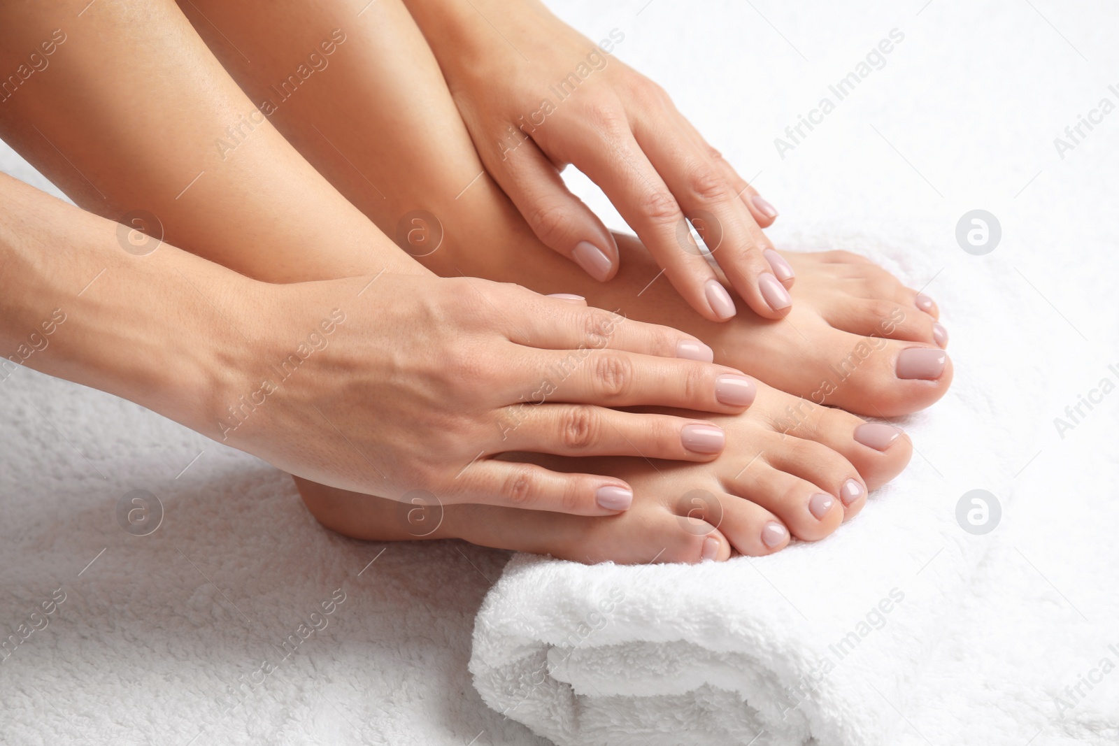 Photo of Woman touching her smooth feet on white towel, closeup. Spa treatment