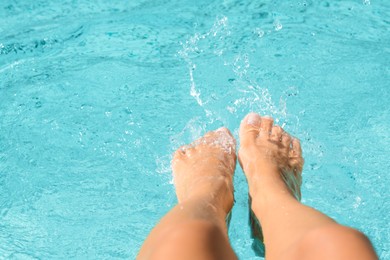 Photo of Woman splashing water in swimming pool with feet, closeup