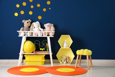 Photo of Different toys near blue wall in child room. Interior design