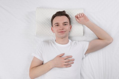 Man lying on orthopedic pillow in bed, top view