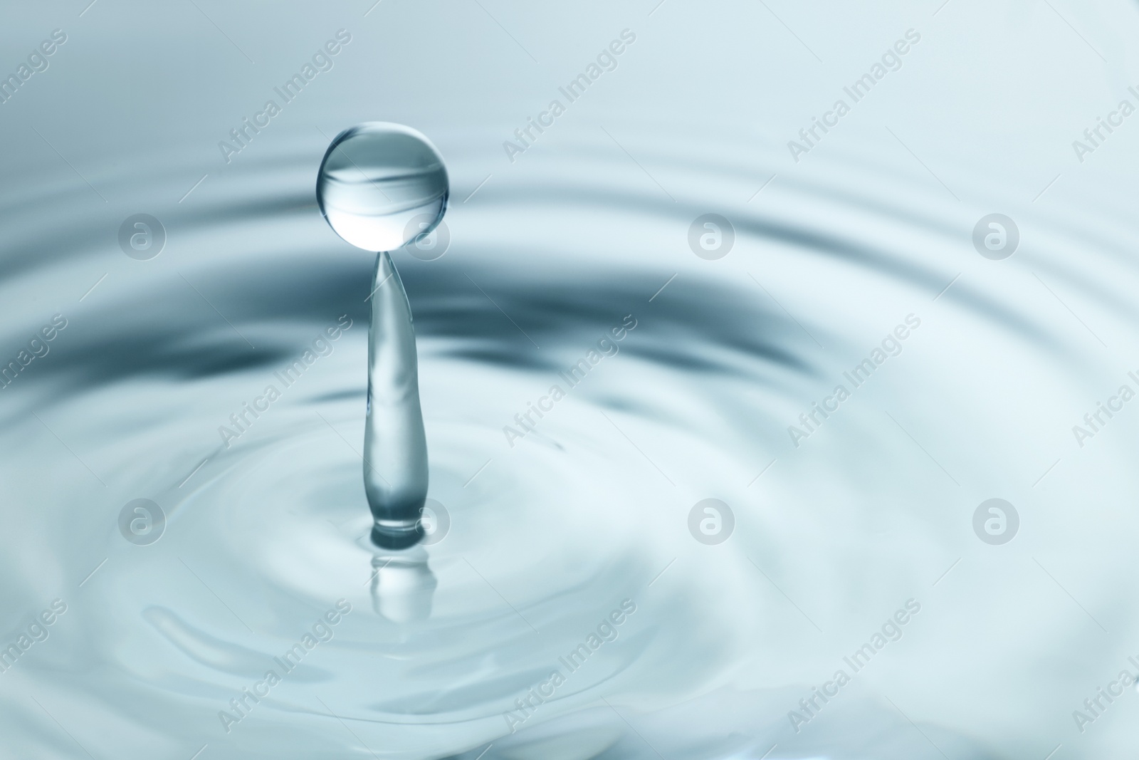 Photo of Splash of clear water with drop on light grey background, closeup